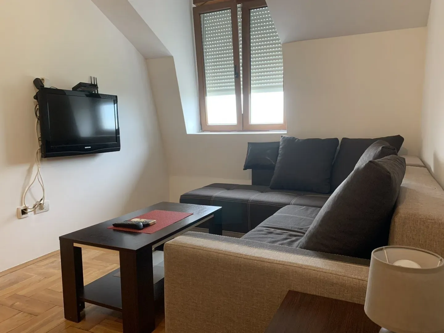 A bright attic living room with a corner sofa and a TV.