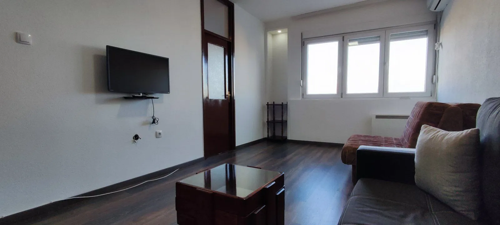 Living room with a wall-mounted TV and furniture.