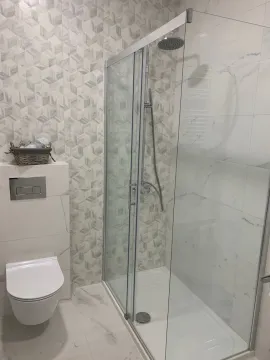 Modern bathroom with a walk-in shower and a wall-mounted toilet. - image 7