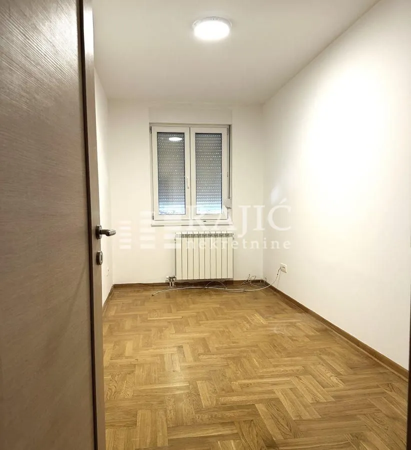 Empty room with parquet flooring and a window.