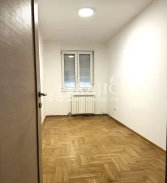 Empty room with parquet flooring and a window. - image 6
