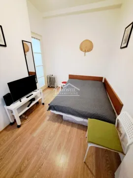Manja spavaća soba sa krevetom, televizorom i drvenim podom. - image 2