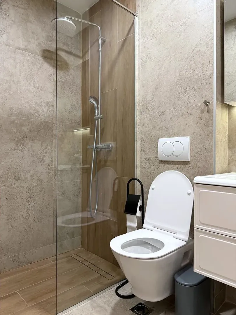 Moderno opremljeno kupatilo sa tuš kabinom i WC šoljom.