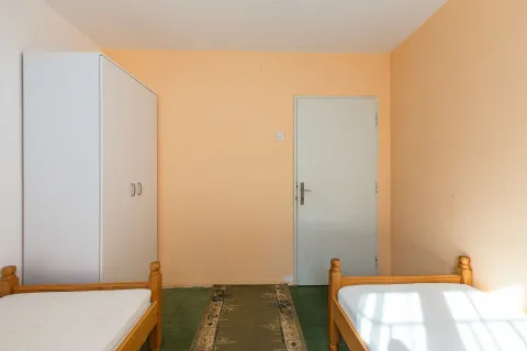 Spavaća soba sa dva drvena kreveta, bijelim garderoberom i vratima. - image 32