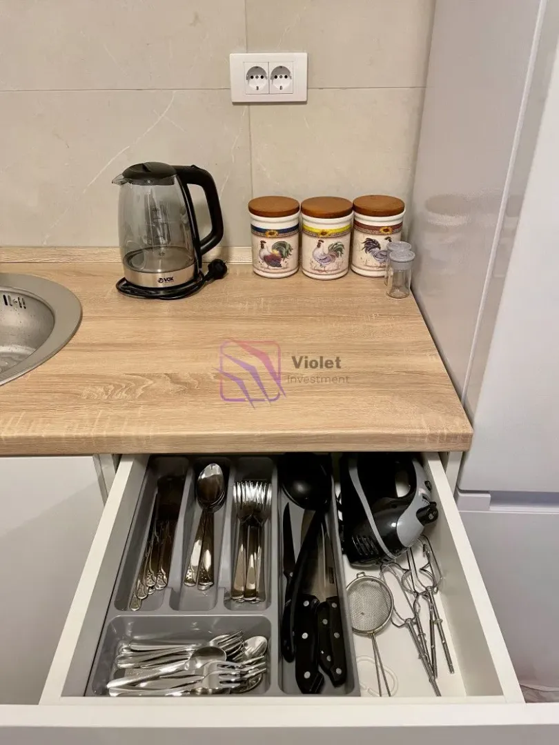Part of the kitchen with a countertop, electric kettle, and an open drawer with cutlery.