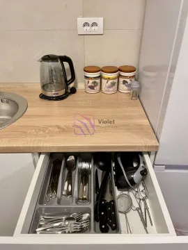 Part of the kitchen with a countertop, electric kettle, and an open drawer with cutlery. - image 6