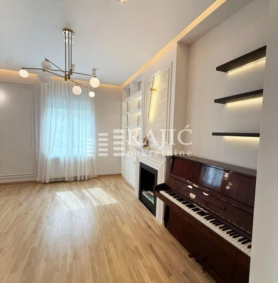 Living room with a fireplace, piano, and wooden floor.