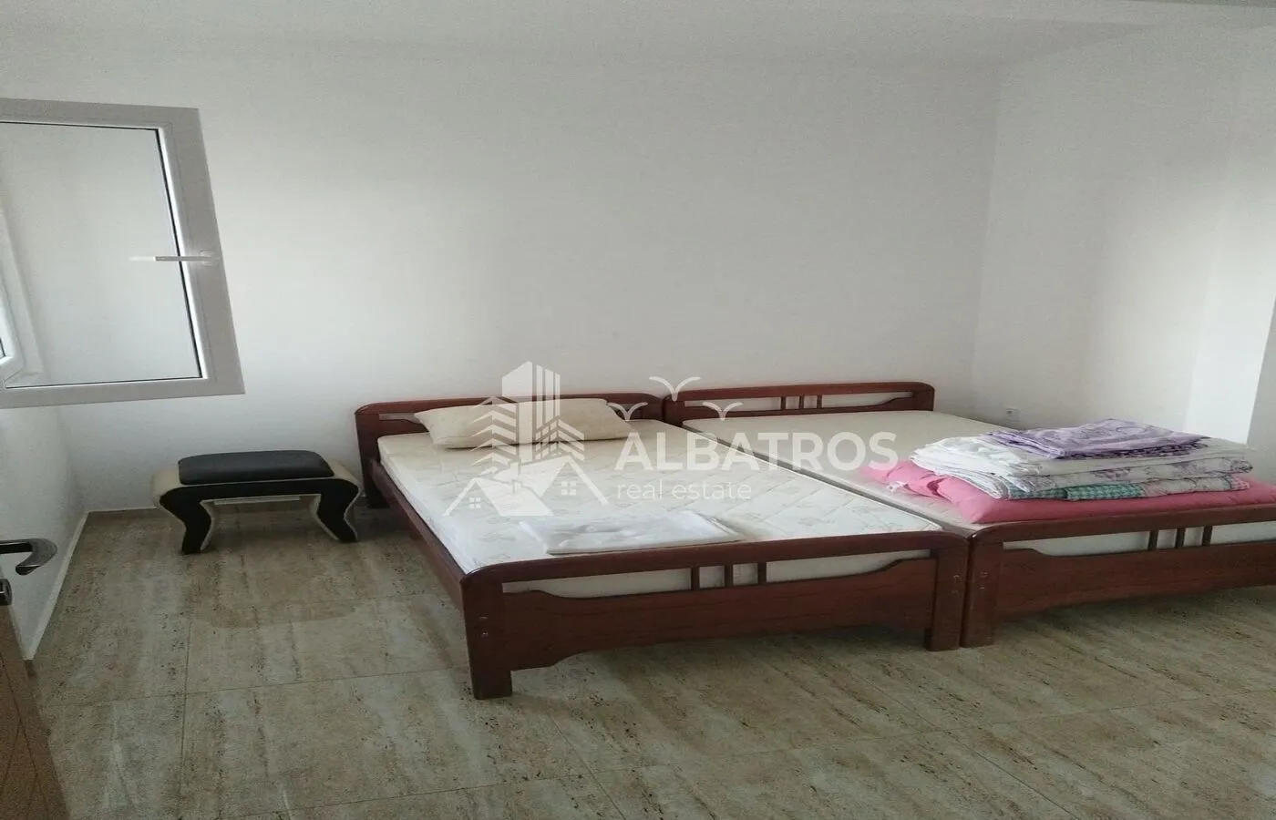Bedroom with two wooden beds and a small window.