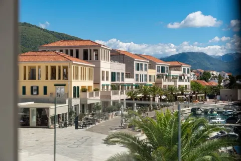 Pogled sa terase na mediteranski trg, zgrade sa narandžastim krovovima i planine u pozadini. - image 15