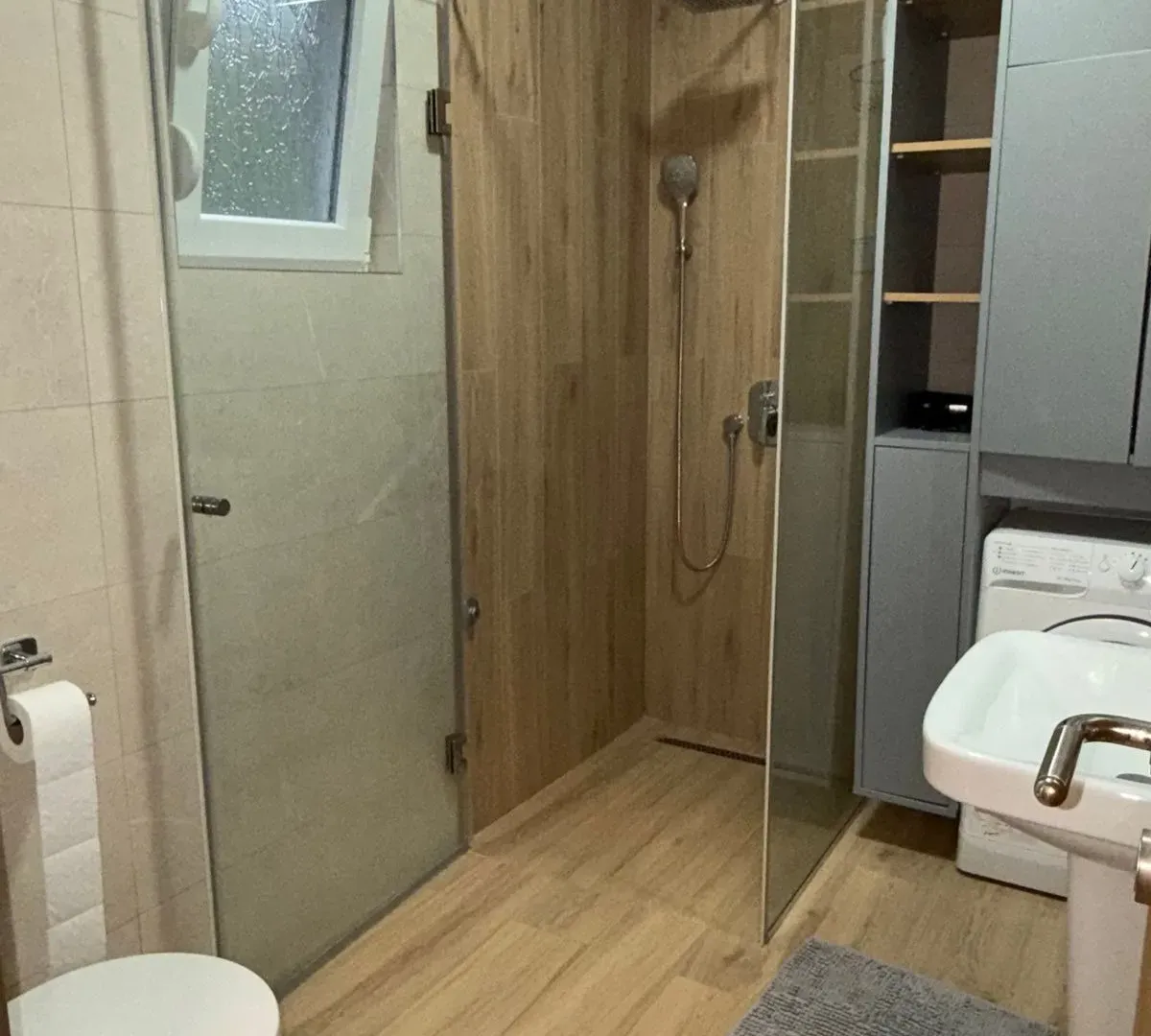 Modern bathroom with a walk-in shower, washbasin, and toilet.