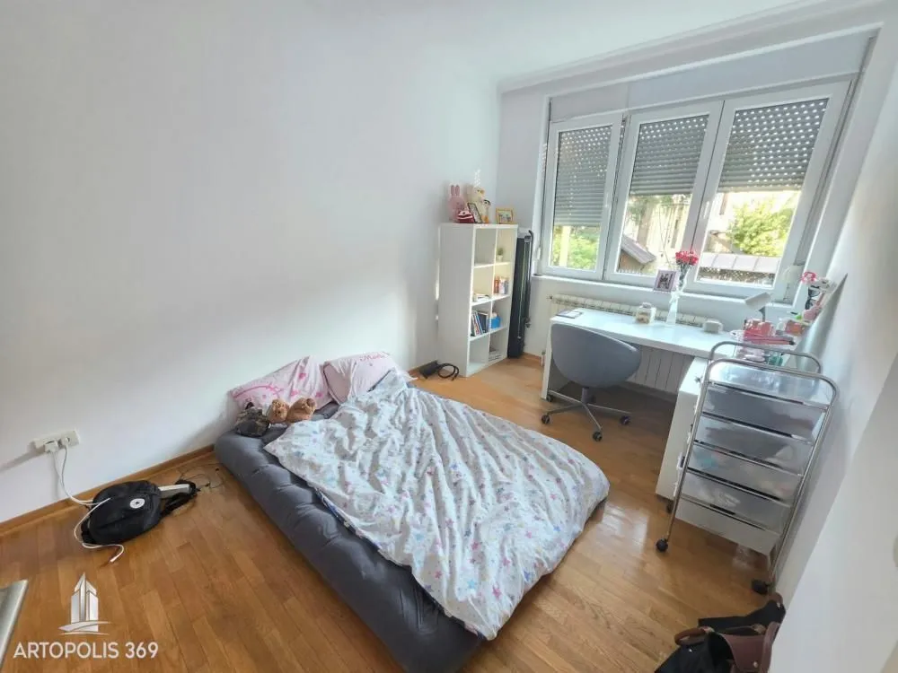 Dečja soba sa krevetom na podu i radnim stolom ispod prozora.
