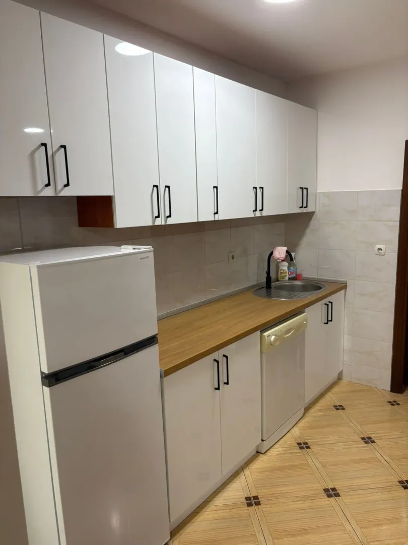 Small white kitchen with a wooden countertop and a refrigerator.