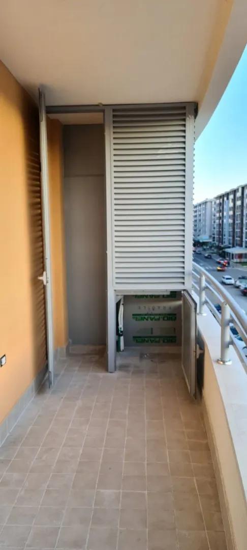 Uzak balkon sa pločicama i ugrađenom ostavom sa žaluzinama.