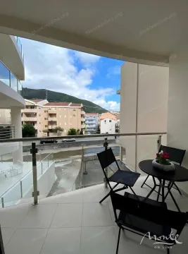 Natkrivena terasa sa stolom i stolicama i pogledom na okolne zgrade i brda. - image 10