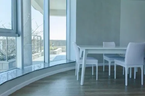 Bright dining area with a white table and chairs next to large windows. - image 5