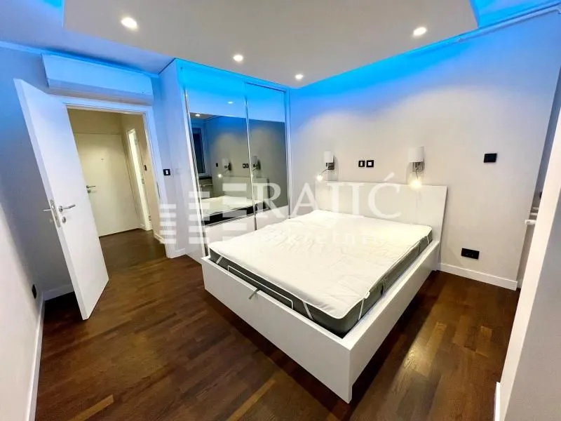 Modern bedroom with a double bed, mirrored wardrobe, and blue lighting.