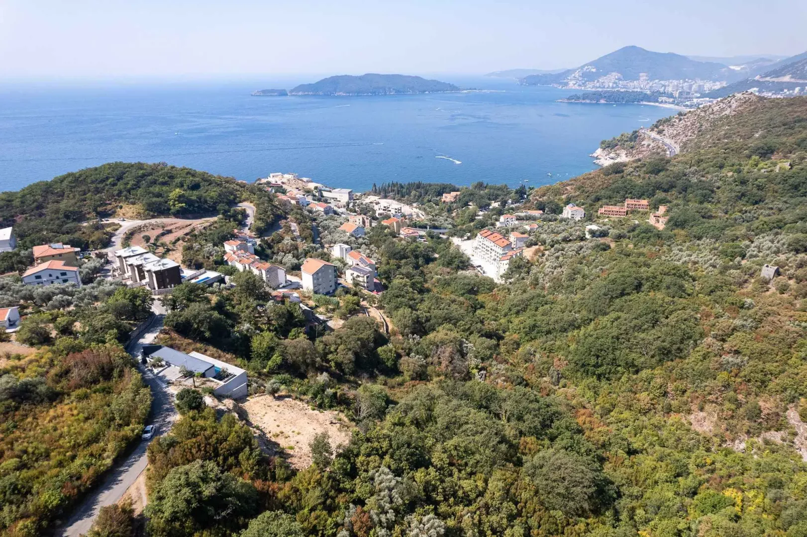 Vazdušni pogled na naselje i obalu mora sa zelenilom.
