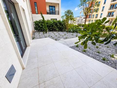 Popločana terasa sa uređenim vrtom ispred moderne zgrade. - image 15