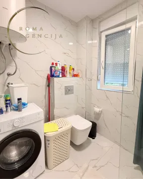 Modern equipped bathroom with a washing machine and walk-in shower. - image 6