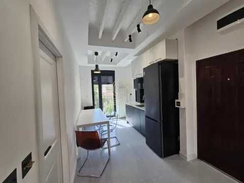 Dugačka kuhinja sa trpezarijskim stolom i crnim frižiderom. - image 4