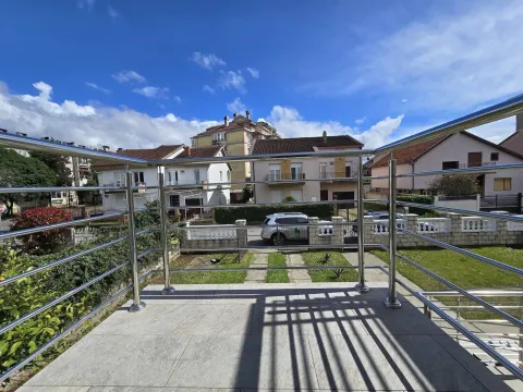 View from the tiled terrace with a metal railing towards the surrounding houses and yard. - image 24
