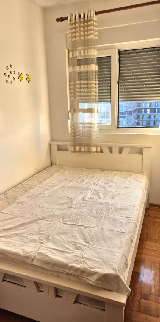 Manja spavaća soba sa bijelim krevetom i prozorom.