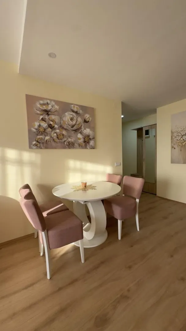 Trpezarijski sto sa roze stolicama i slikom na zidu u dnevnom boravku.