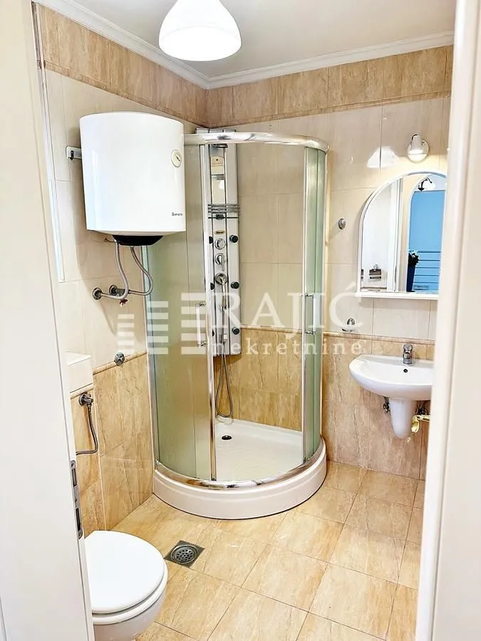 Small bathroom with a shower cabin, sink, and toilet.