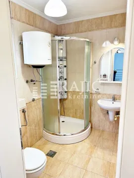 Small bathroom with a shower cabin, sink, and toilet. - image 20