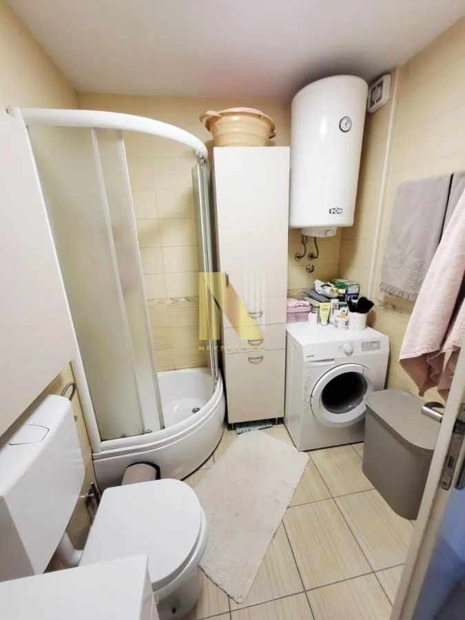 Manje kupatilo sa tuš kabinom, WC šoljom, veš mašinom i bojlerom.