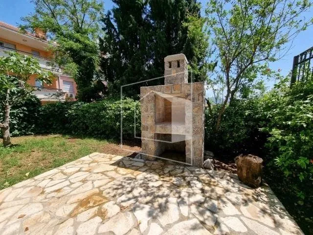 Yard with a stone barbecue and paved area.