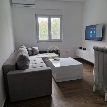 Dnevna soba sa ugaonom garniturom, stočićem i televizorom na zidu. - image 2
