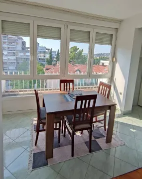 Dining area with a wooden table and chairs by large windows overlooking the city. - image 2