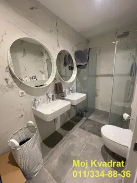 Modern bathroom with two sinks, a walk-in shower, and round mirrors. - image 14