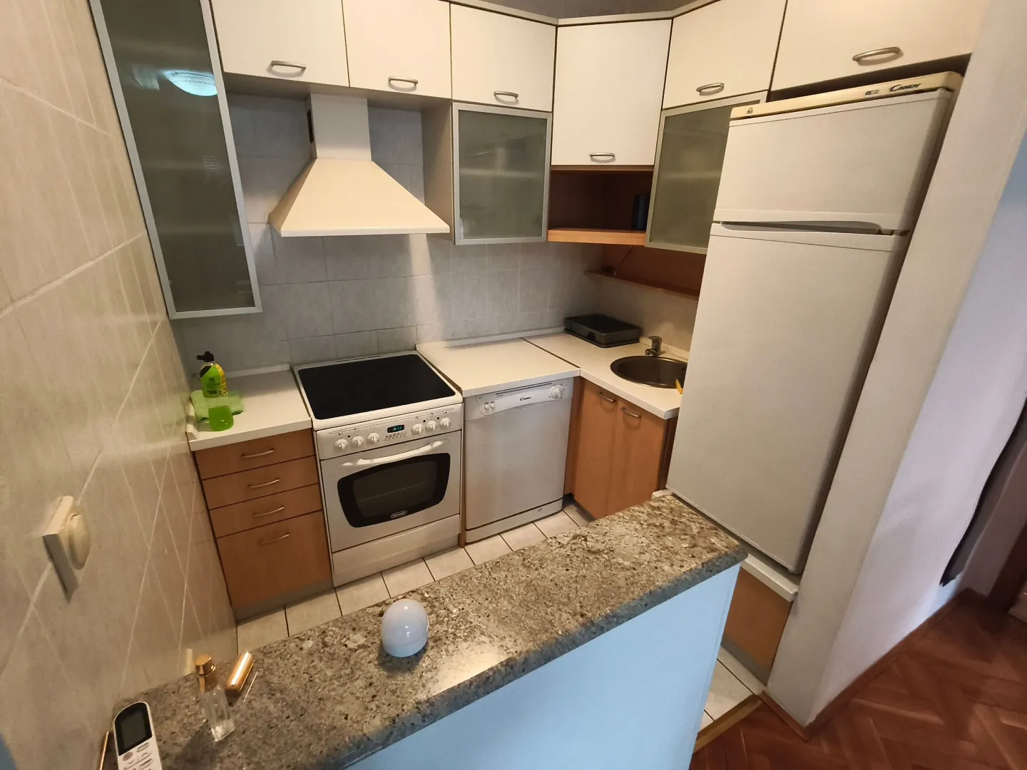 Small equipped kitchen with white units and a breakfast bar.
