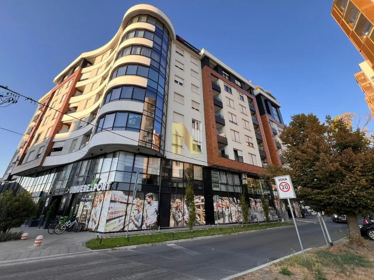 Pogled na spoljašnjost moderne stambeno-poslovne zgrade sa supermarketom u prizemlju.