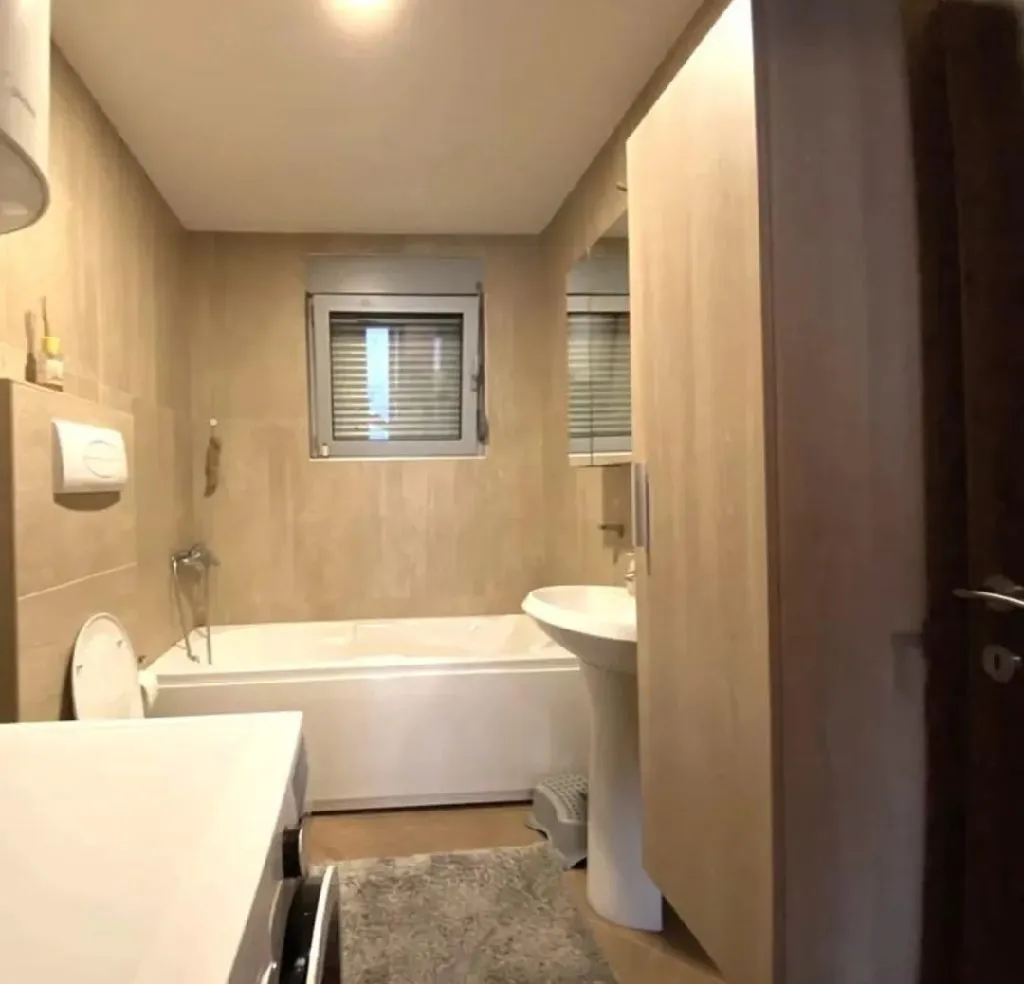 Modernly equipped bathroom with a bathtub and sink in beige tones.