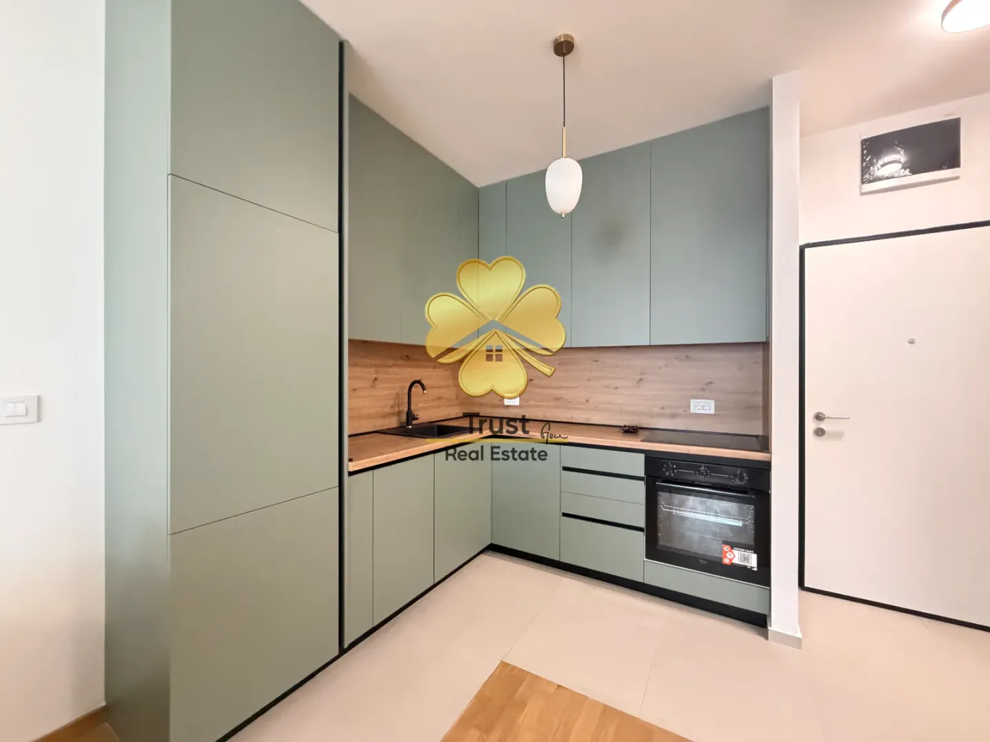 Modern kitchen with green cabinets and a wooden countertop.