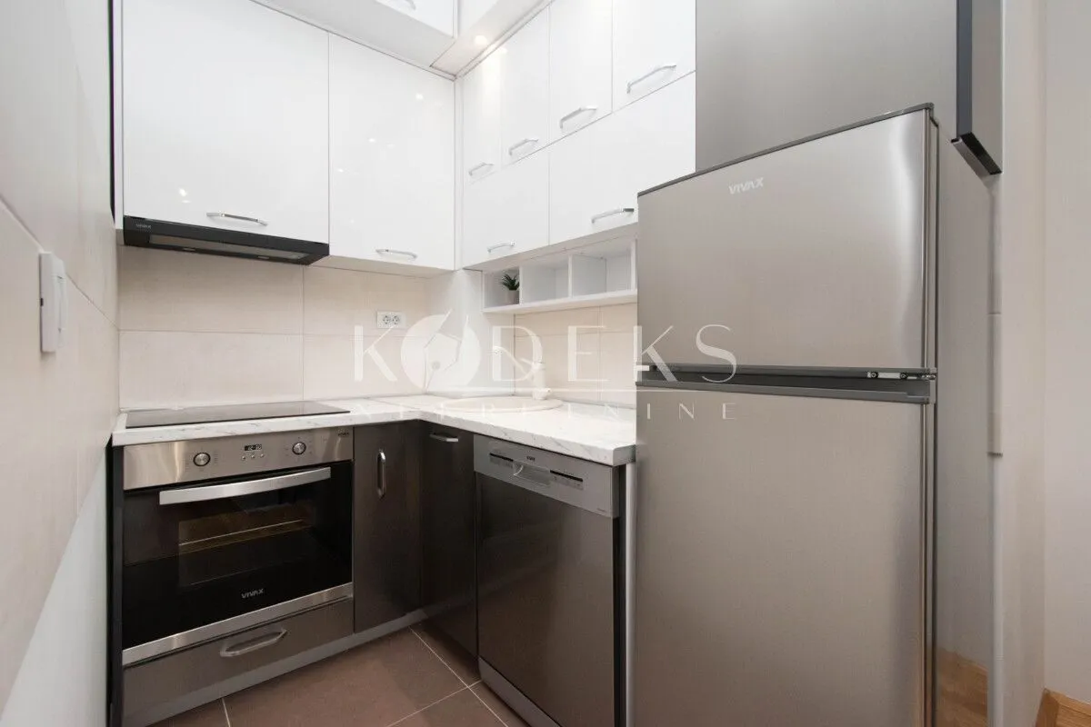 Small equipped kitchen with white cabinets and stainless steel appliances.
