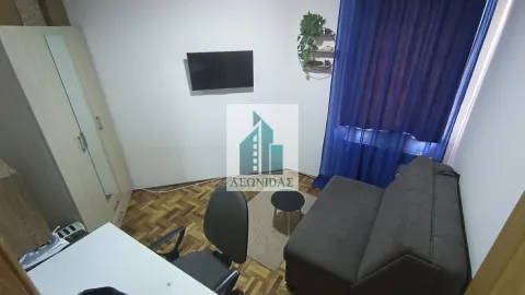 Manja dnevna soba sa kaučem, garderoberom, radnim stolom i televizorom na zidu. - image 10
