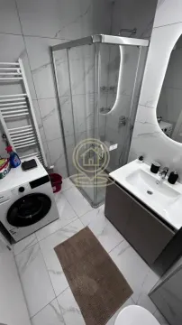Modern bathroom with a shower cabin, washbasin, and washing machine. - image 11