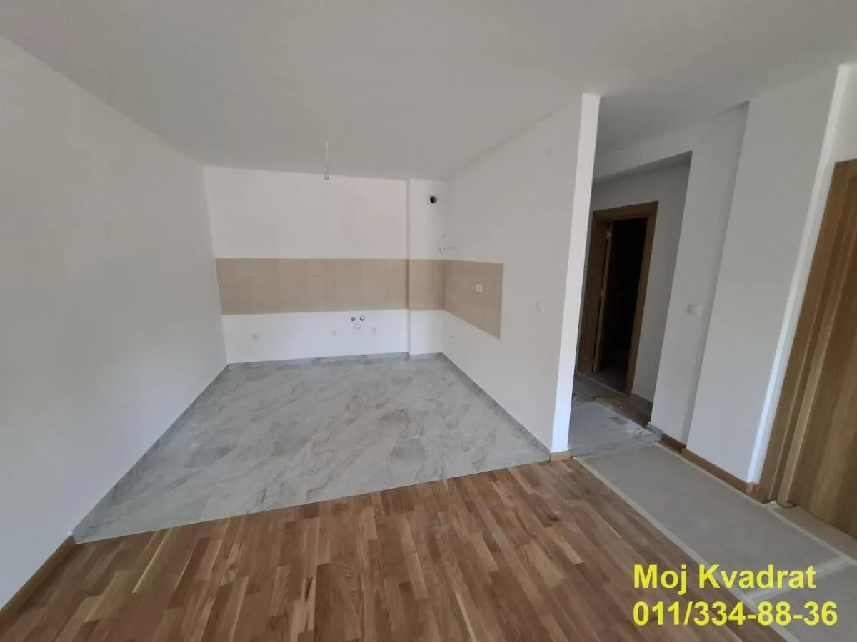 Prazna kuhinja sa pripremljenim priključcima i keramičkim pločicama na zidu.