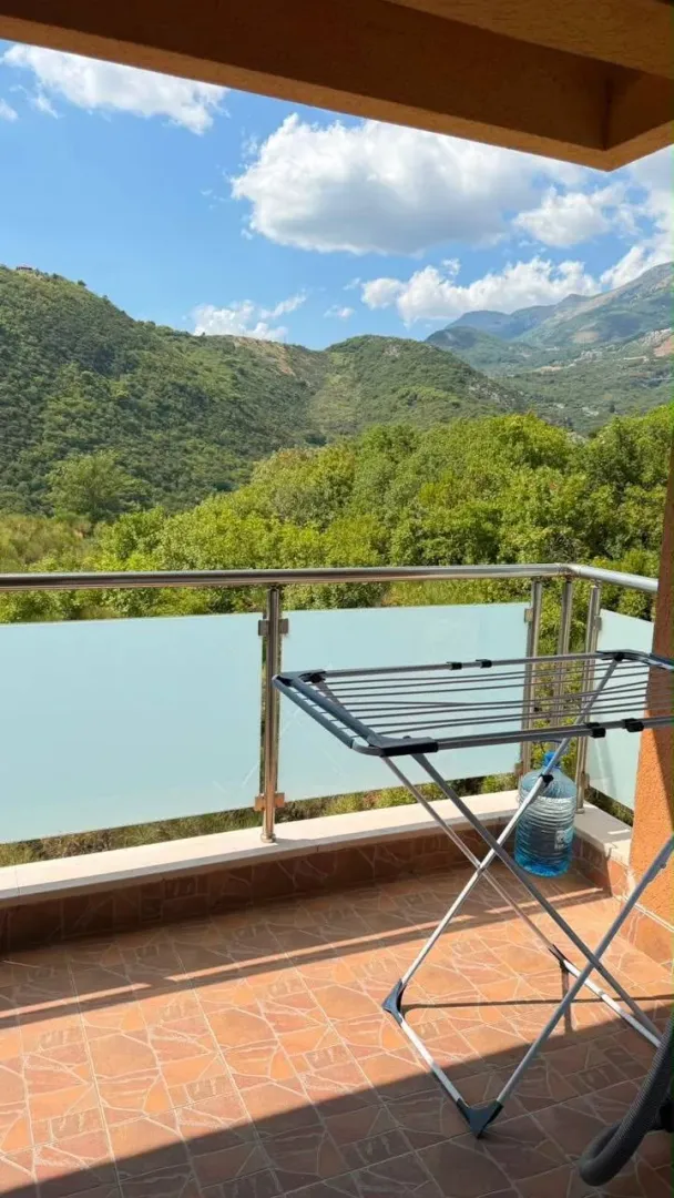 Terrace with a metal railing and a view of hills and nature.
