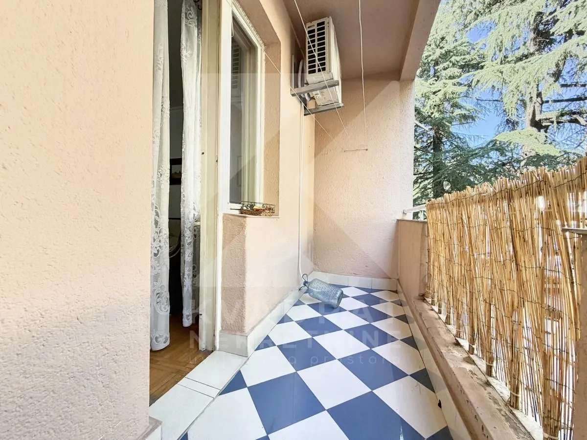 Covered balcony with blue and white tiled flooring and a wooden fence.