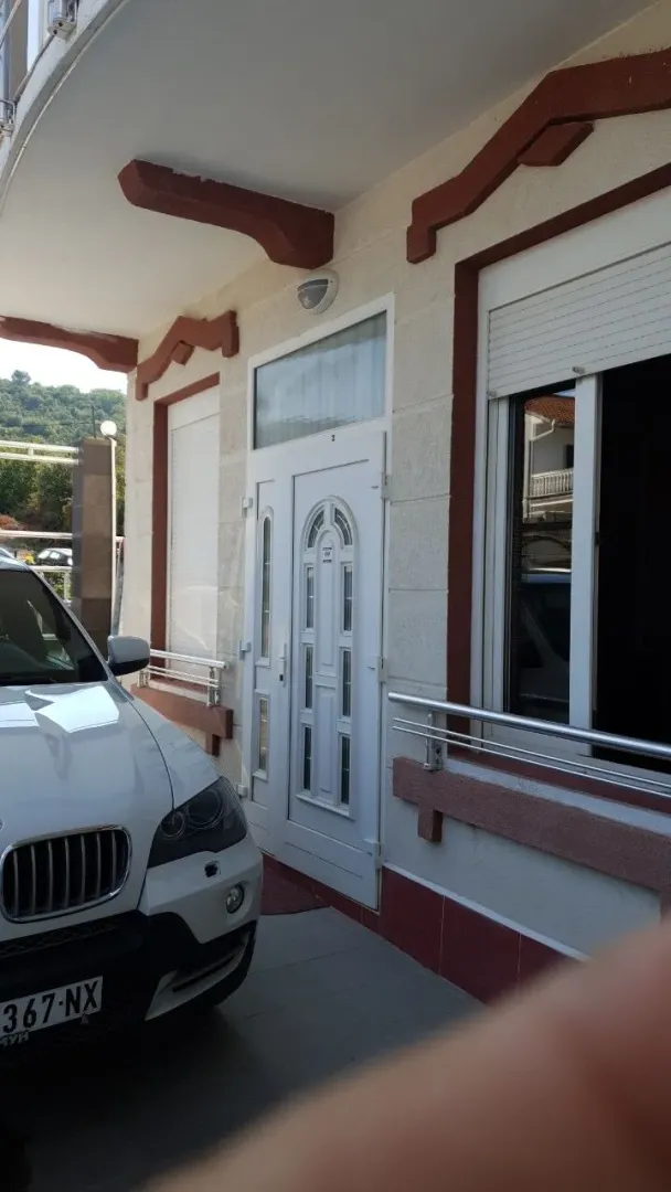 Ulaz u kuću sa bijelim vratima i parkiranim automobilom ispred.