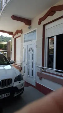 Ulaz u kuću sa bijelim vratima i parkiranim automobilom ispred. - image 6