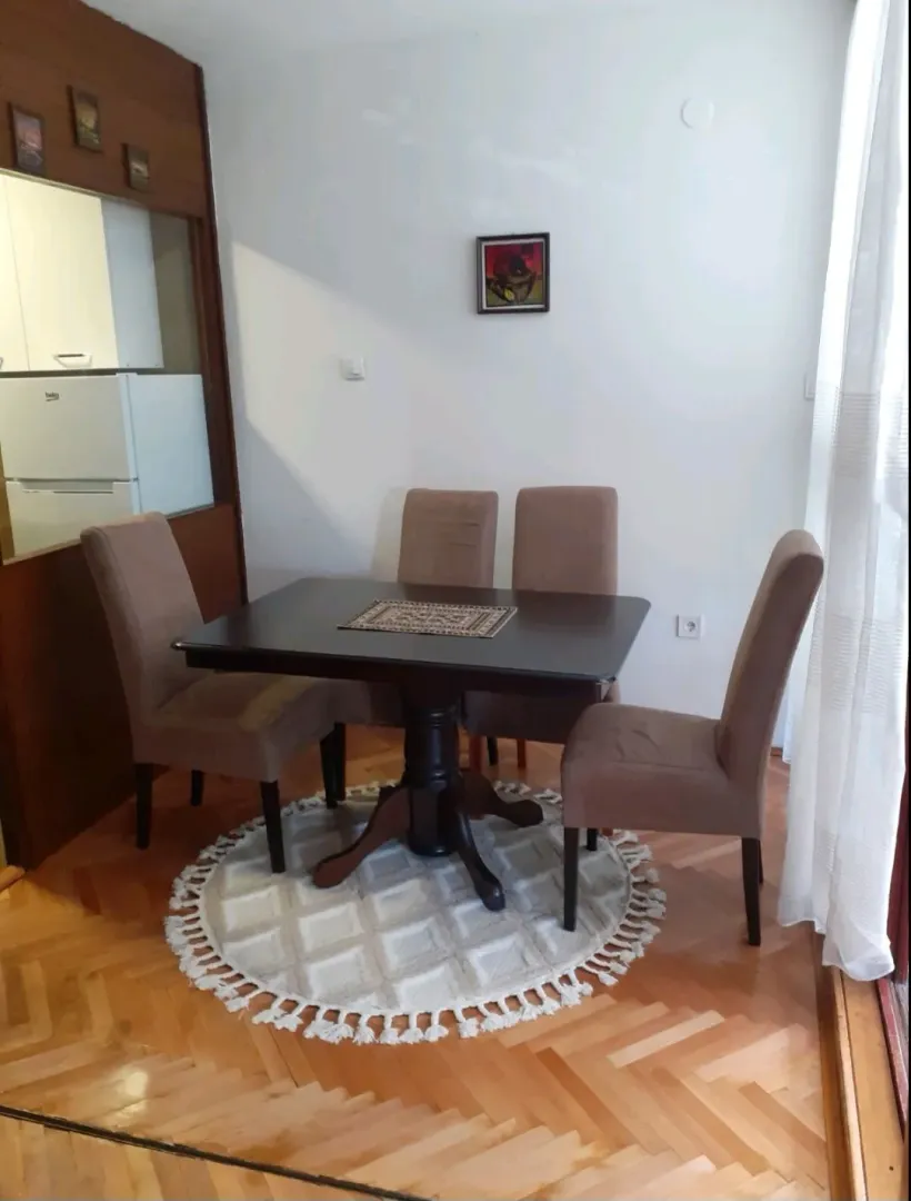 Trpezarija sa stolom, četiri stolice i drvenim podom.