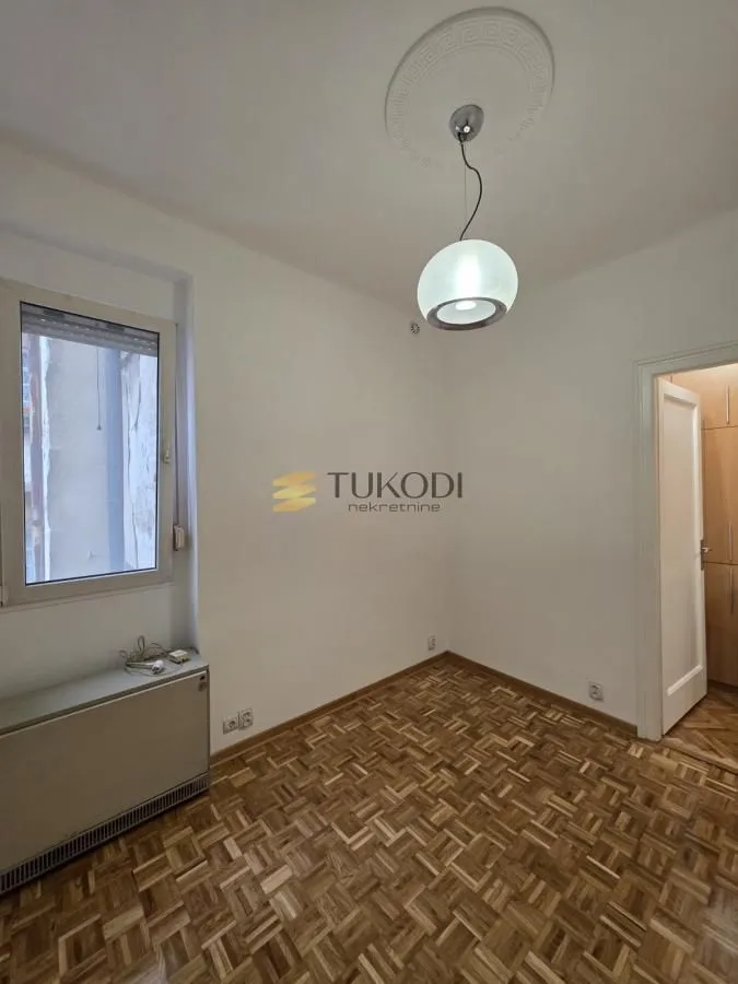 Empty room with parquet flooring and a ceiling light.