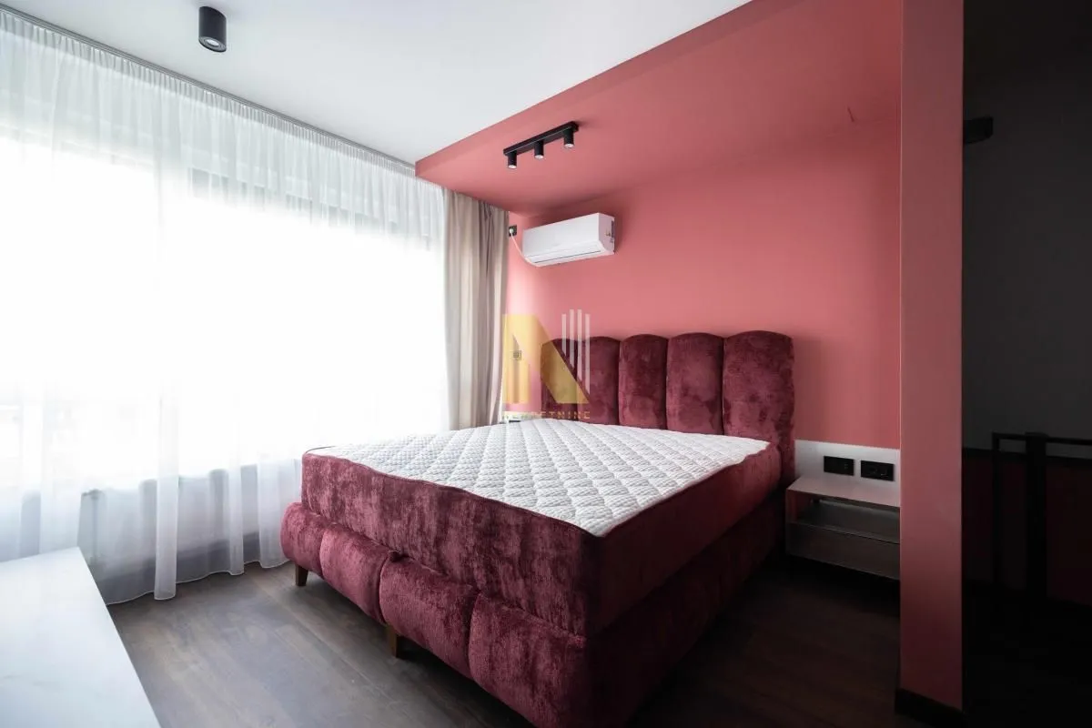 Moderna spavaća soba sa bračnim krevetom i ružičastim zidovima.