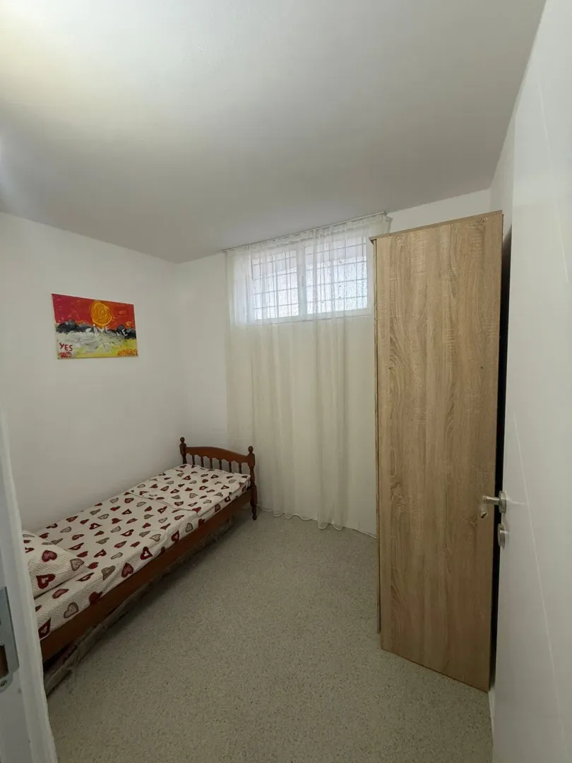 Small bedroom with a bed, wardrobe, and window.